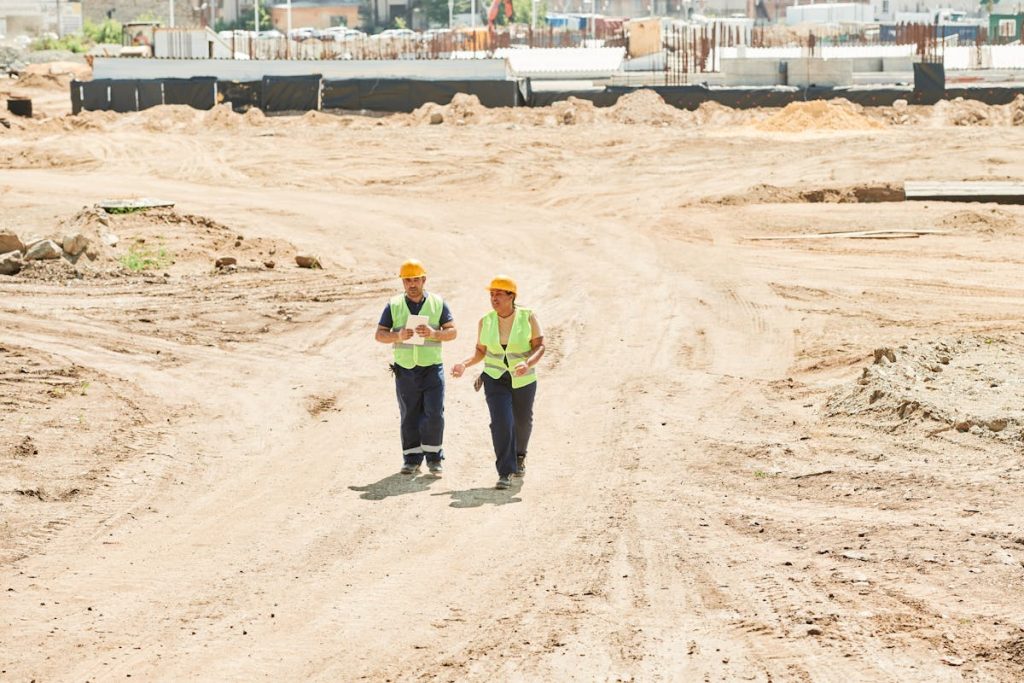 man and woman in helmets and reflective vests on a construction site